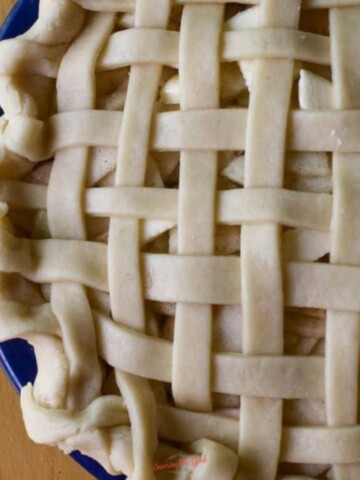 Easy Crisco Pie Crust Recipe used to make a lattice top pie in a blue pie plate.